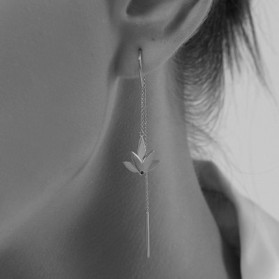 Profile of a woman wearing two different Lotus earrings in rhodium-plated sterling silver – one with chain and one without – styled with polished finish and black cubic zirconia, highlighting the contrast between classic minimalism and sophisticated elegance.