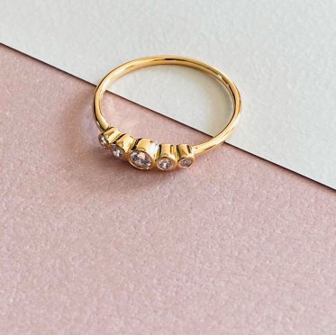 Gold-plated Cham Bi ring with five hand-set cubic zirconia, displayed in a natural setting with soft light and Scandinavian aesthetics – a feminine and sustainable piece by East Copenhagen.
