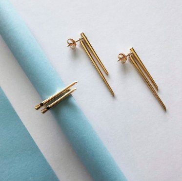 Three Chopstick jewelry pieces by East Copenhagen – earrings and rings in gold-plated and rhodium-plated sterling silver, elegantly displayed in a minimalist setting with natural light and Scandinavian aesthetics.