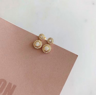 Flower earrings by East Copenhagen in gold-plated sterling silver with sparkling zirconia, displayed in a feminine setting with soft light and natural elements – a handcrafted piece with hidden floral structure and modern elegance